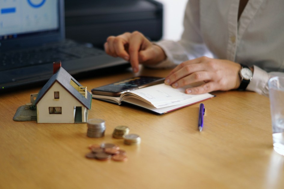 Foto conceitual de mercado imobiliário. com pessoa fazeno contas em mesa perto de maquete de casa