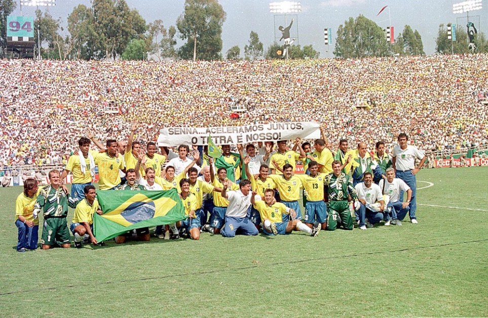 Jogadores e comissão técnica do Brasil posam após a partida final em Rose Bowl, Pasadena na Copa de 94 dos Estados Unidos Onde o Brasil venceu a Itália por 3 x 2 na disputa de pênaltis. Ao fundo uma faixa com os dizeres "Senna... aceleramos juntos, o tetra é nosso!"
