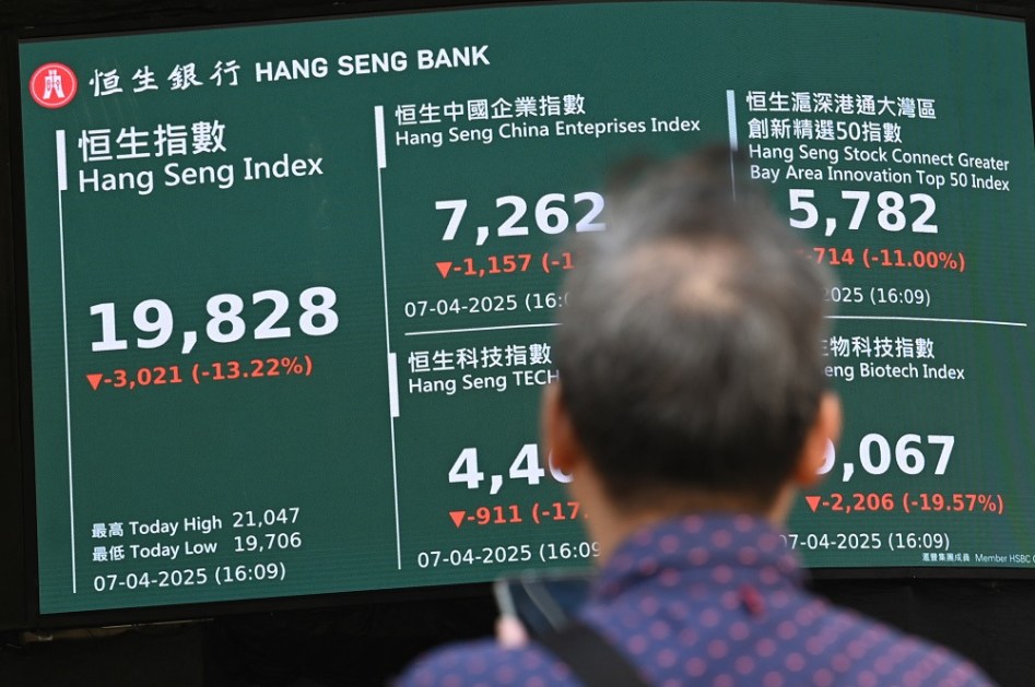 Um homem observa um painel eletrônico exibindo o preço de fechamento do Índice Hang Seng em Hong Kong