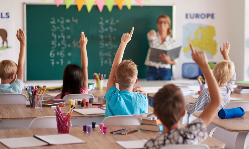 Alunos com mão levantada em sala de aula