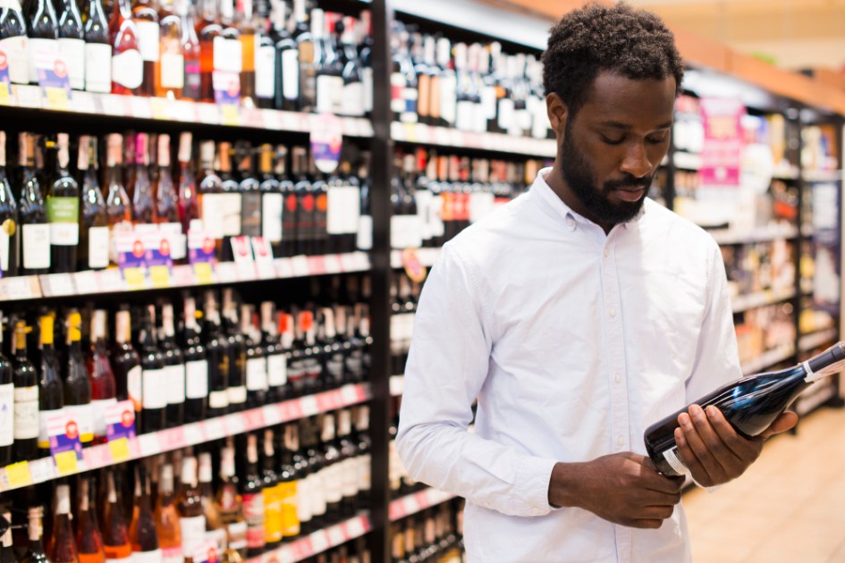 Homem escolhe vinho em seção de bebidas