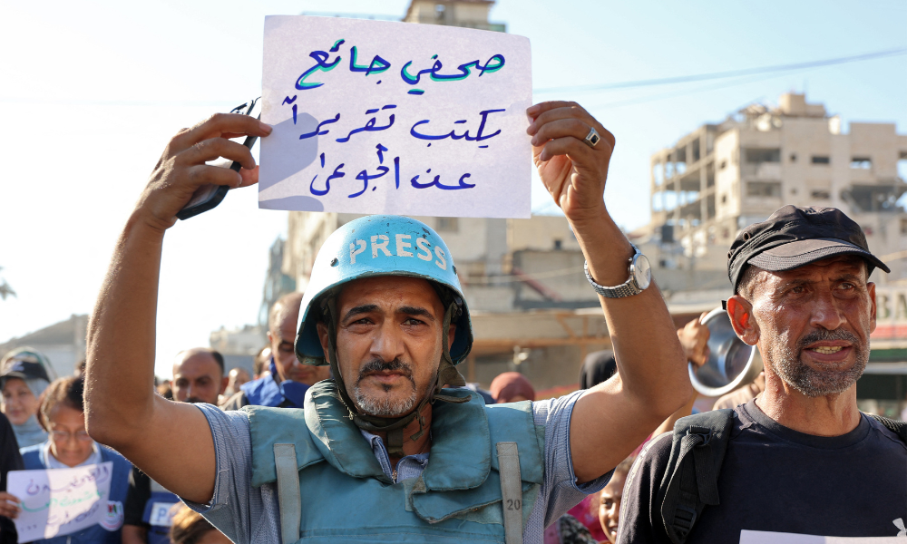 FOTOGRAFIA PRINCIPAL - Um manifestante segura uma placa com os dizeres em árabe "um jornalista faminto escreve uma reportagem sobre os famintos" durante um protesto de jornalistas contra a fome no distrito de Rimal, na Cidade de Gaza, em 19 de julho de 2025. (Foto de Omar AL-QATTAA / AFP)