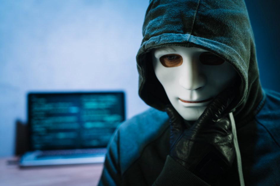 Hacker com máscara na frente do laptop