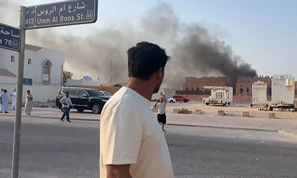 Esta captura de tela, tirada de uma filmagem da AFPTV, mostra um homem observando a fumaça subindo após as explosões na capital de Doha, Catar, em 9 de setembro de 2025. Um oficial militar israelense disse à AFP que os militares realizaram ataques aéreos em Doha em 9 de setembro, em uma operação que teve como alvo líderes seniores do grupo militante palestino Hamas. (Foto de Jacqueline PENNEY / AFPTV / AFP)