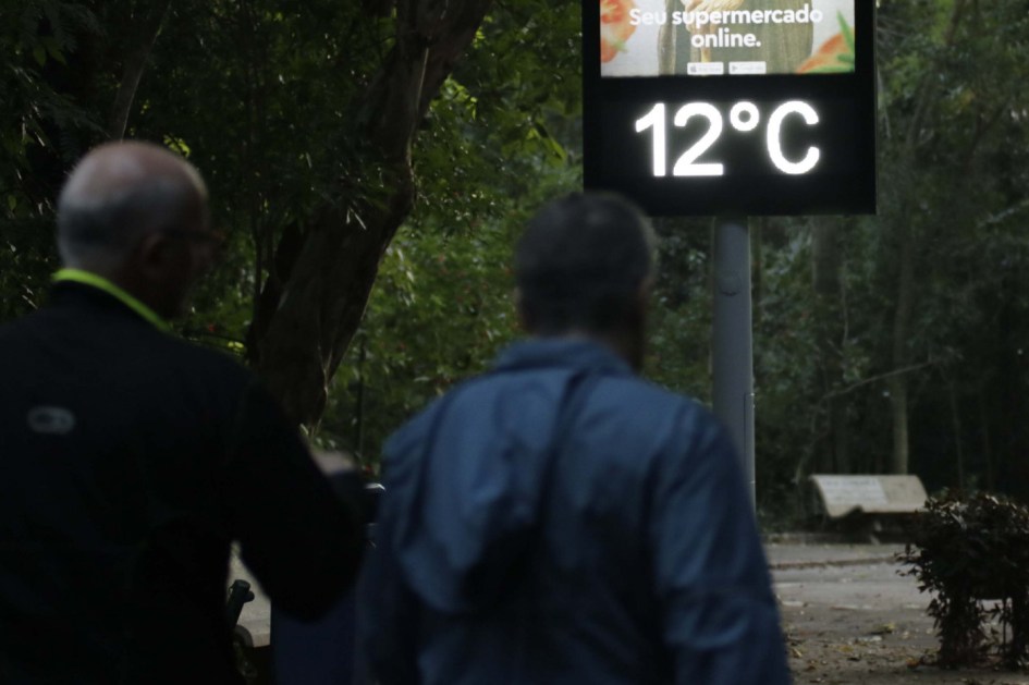 Pessoas andam com casacos e termômetro marca 12ºC