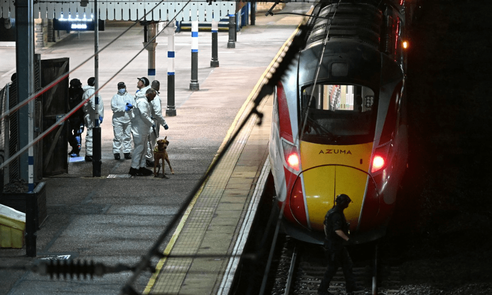 Policiais e um agente canino trabalham na plataforma na estação de Huntingdon, em Huntingdon, leste da Inglaterra, após um esfaqueamento em um trem