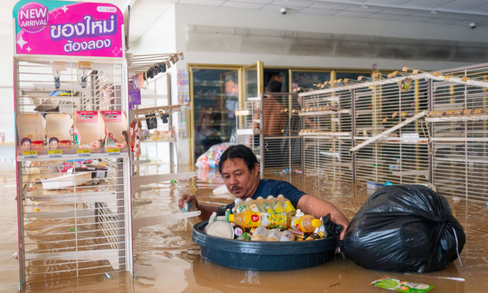 Um homem empurra um recipiente cheio de bebidas enquanto caminha pela água em uma loja de conveniência 7/11 inundada em Hat Yai, na província de Songkhla, no sul da Tailândia, em 26 de novembro de 2025, quando graves inundações afetaram milhares de pessoas no sul do país após dias de fortes chuvas. Dezenas de milhares de pessoas na Tailândia e na vizinha Malásia foram deslocadas por inundações generalizadas, com ruas submersas, casas inundadas e pelo menos 34 mortos, disseram autoridades em 26 de novembro.