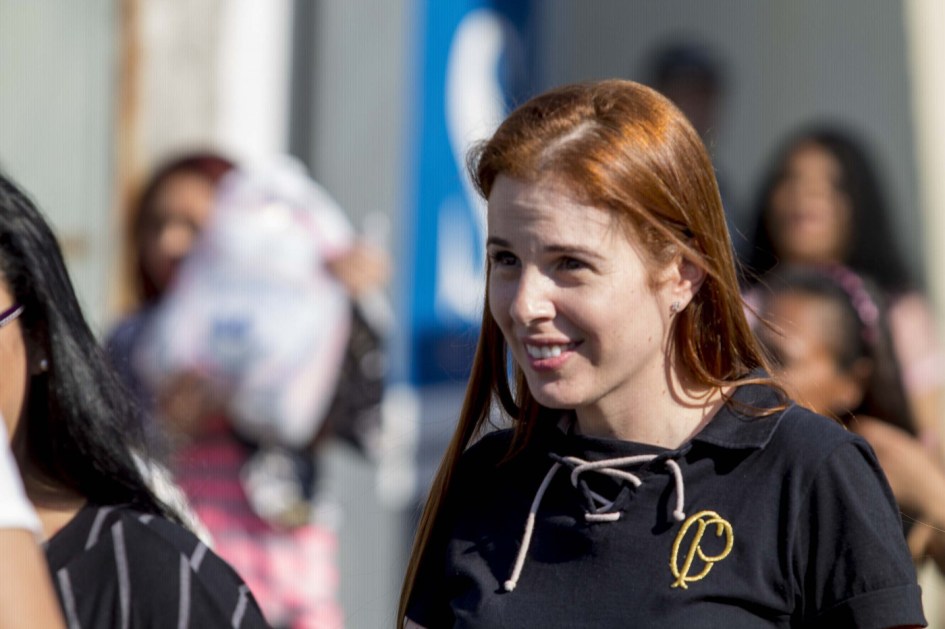 Suzane von Richthofen de cabelos lisos e ruivos e camiseta preta deixando a prisão. Ela sorri