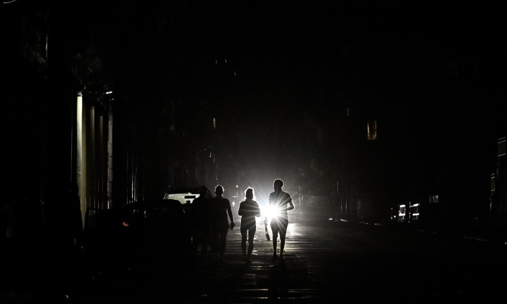 Pessoas caminham por uma rua sem eletricidade durante o apagão nacional em Havana