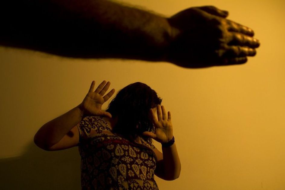 Palma de mão em primeiro plano e mulher com as mãos no rosto em segundo plano