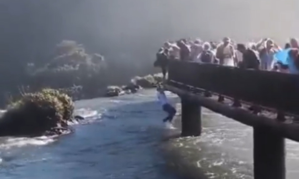 Captura de tela de vídeo em que homem pula de passarela nas Cataratas do Iguaçu para recuperar seu celular que havia caído.