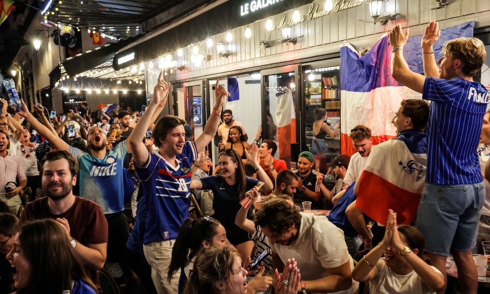 Apoiadores comemoram a vitória da França por 2 a 0 sobre o Marrocos nas quartas de final da Copa do Mundo, com bandeiras e camisas francesas visíveis, em Chatelet-Les-Halles, Paris, Ile-de-France, França, 10 de julho de 2026