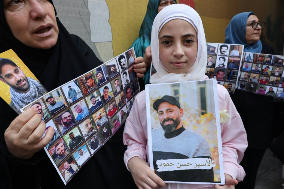 Familiares de prisioneiros e detidos em prisões israelenses carregam fotos de seus parentes durante um protesto de solidariedade convocado pelo Comitê de Representantes de Prisioneiros e Libertados de Prisões Israelenses, em frente à sede da Cruz Vermelha Internacional em Beirute, em 12 de agosto de 2026. (Foto de Anwar AMRO / AFP)