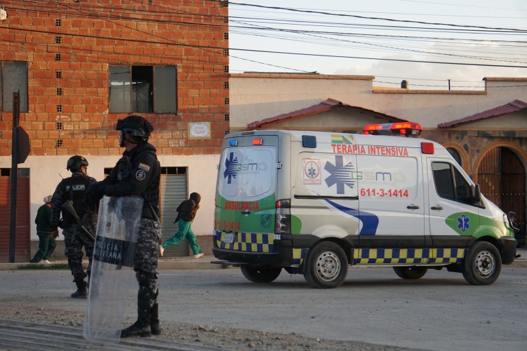 Esta imagem divulgada pela APG Noticias mostra policiais perto de uma ambulância no local de uma explosão em um quartel do exército em Viacha, Bolívia, em 4 de setembro de 2026. Pelo menos duas pessoas morreram e 59 ficaram feridas em uma forte explosão em uma instalação militar que armazenava material pirotécnico na Bolívia, informou a polícia em um balanço atualizado, acrescentando que a causa da explosão ainda está sendo investigada.