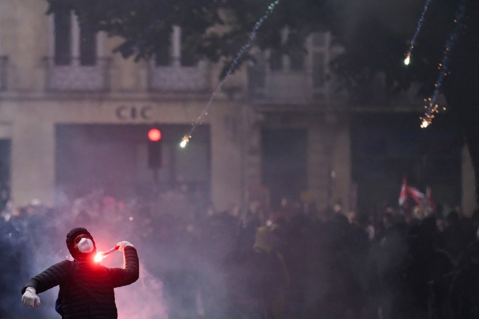 Um manifestante atira um sinalizador de fumaça em direção aos xandarmas franceses durante uma demonstração em protesto contra o "alto custo de vida", em Bordéus, no sudoeste da França, em 17 de outubro de 2026, como parte de uma convocação nacional de mobilização que reúne vários grupos expressando sua indignação: ex-integrantes dos "Coletes Amarelos", estudantes do ensino médio e universitários, ativistas climáticos e até mesmo agricultores.