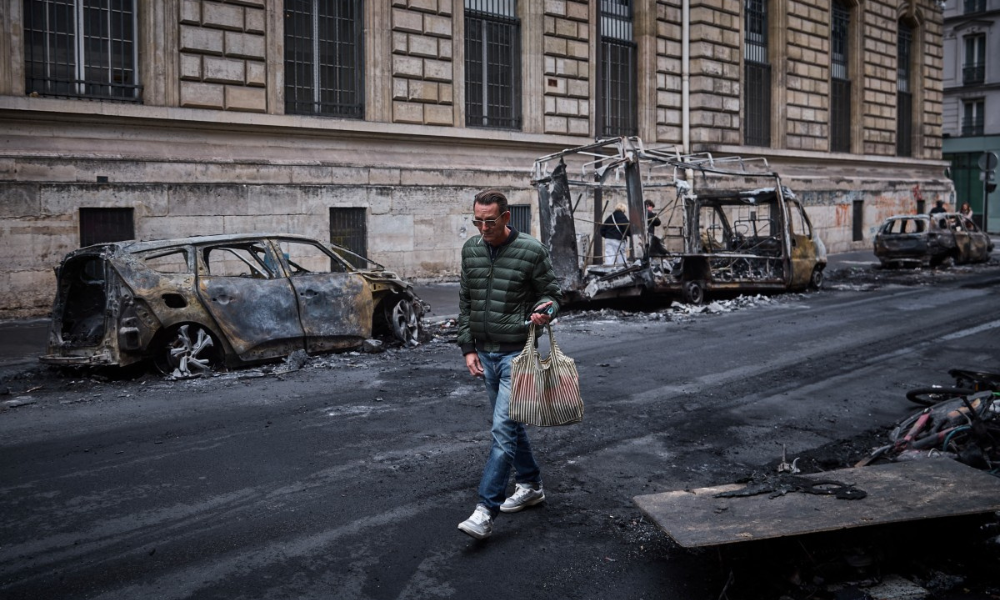 Homem passa por uma fileira de veículos carbonizados, após um protesto no centro de Paris, na França