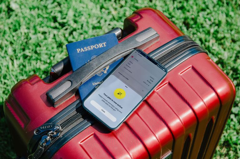 Smartphone e passaporte apoiados sobre uma mala de viagem