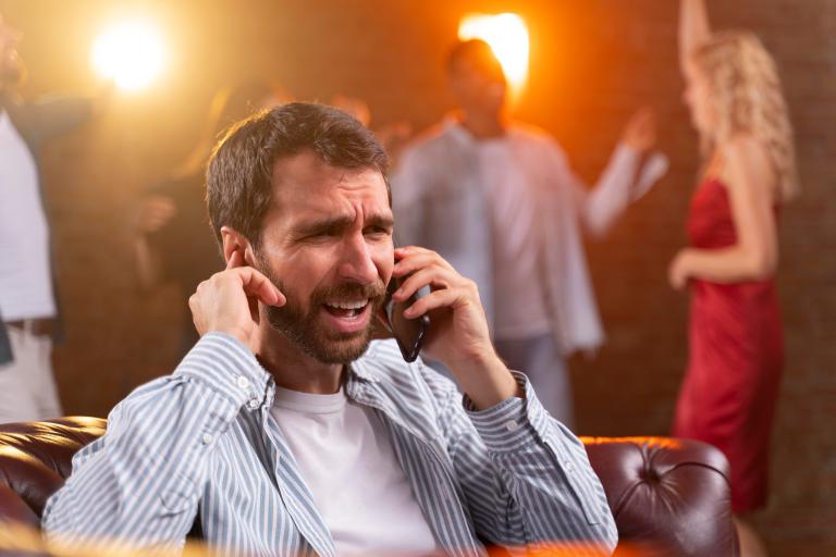 Homem tenta falar ao telefone durante festa