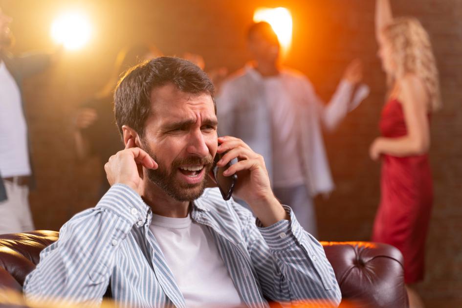 Homem tenta falar ao telefone durante festa